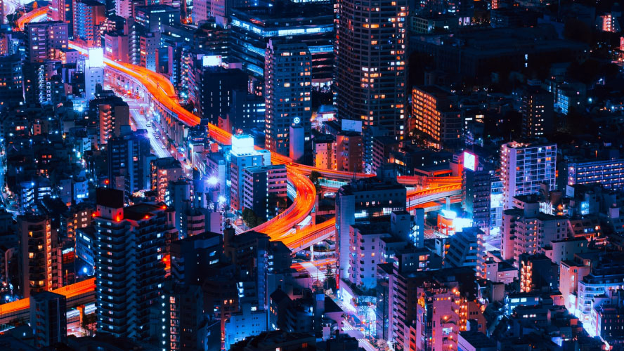 An aerial view of a city at night showcasing illuminated traffic lights amidst the urban landscape.