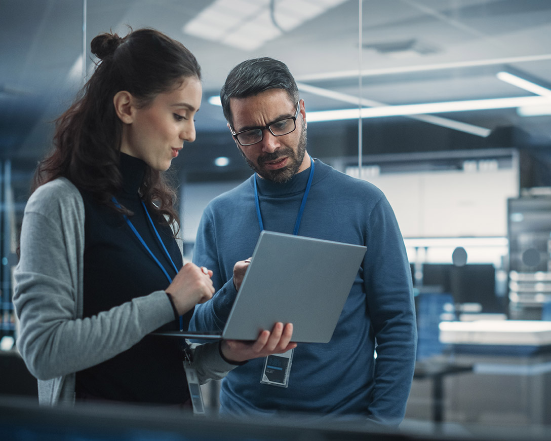Azure AI &ndash; Two engineers use a laptop to analyze AI software in a high tech research facility